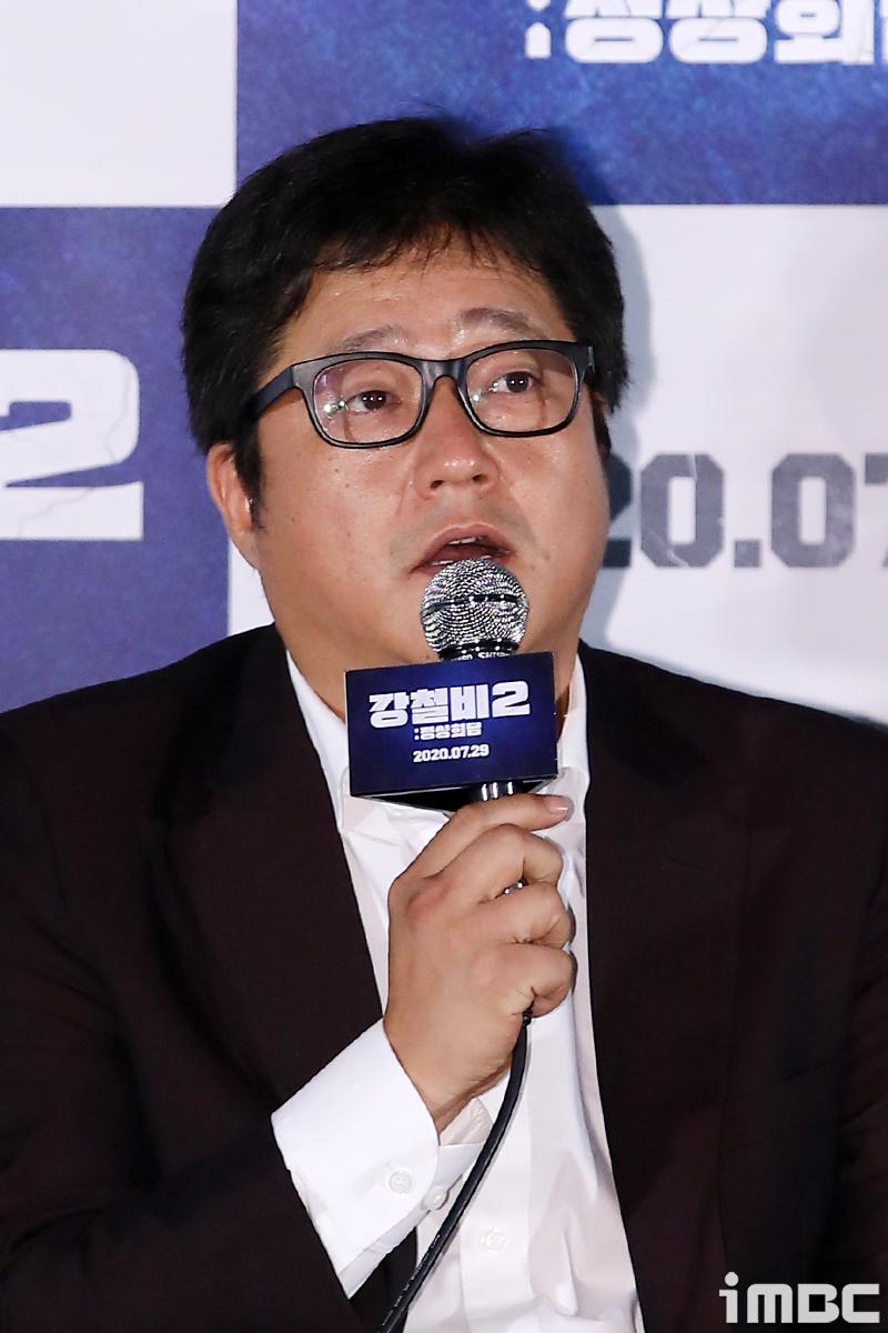 韓国映画『強制執行2』の記者会見においてマイクを持つ人物がスピーチをしている様子。著作権はiMBC芸能にある。