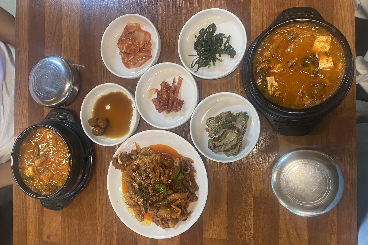 Délicieux repas coréen composé de divers plats traditionnels, y compris le kimchi jjigae et du porc frit, servi près du parc MBC Daejanggeum, souvent fréquenté par des acteurs.