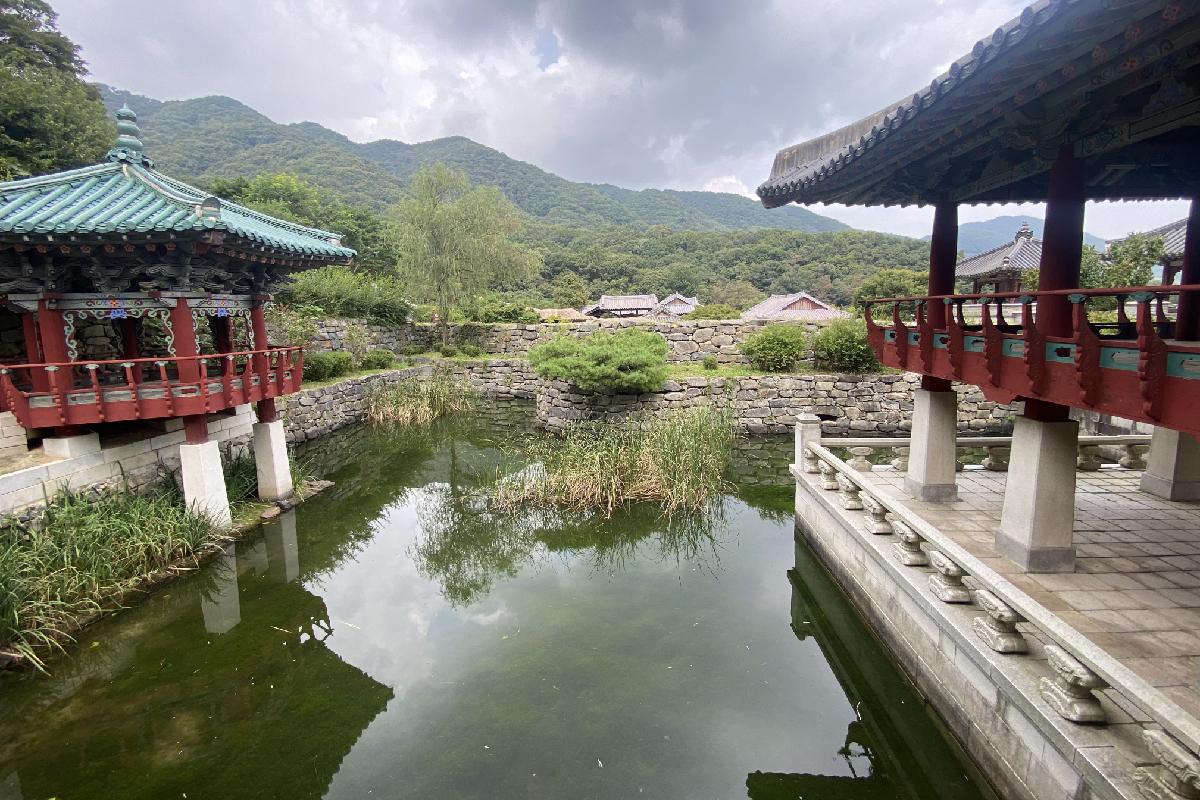 Vue sur un étang calme entouré de pavillons traditionnels coréens au parc Yongin Daejanggeum, un lieu de tournage célèbre de dramas coréens historiques.