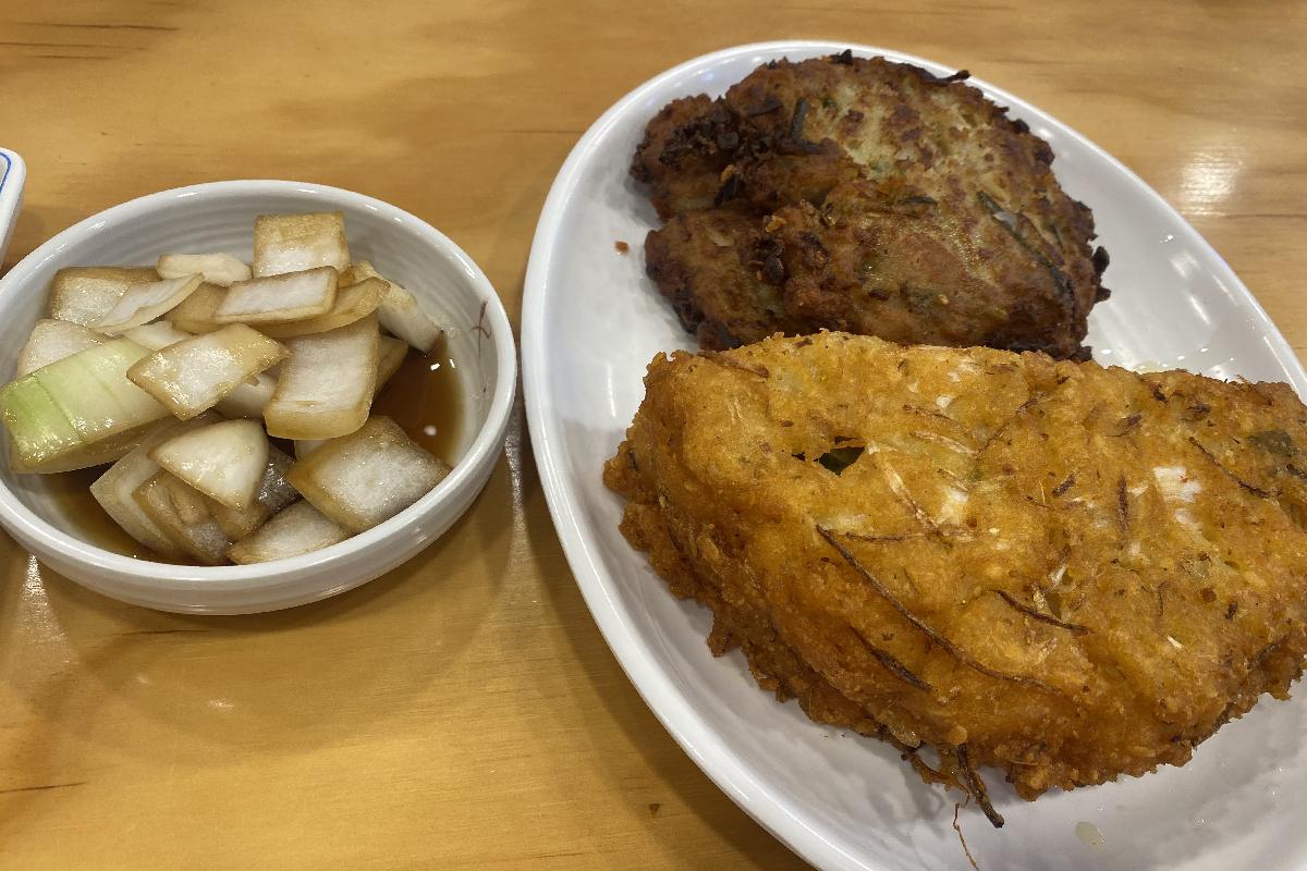 Assiette de crêpes de haricots mungo servies avec une sauce à base d'oignons sur le côté au marché de Gwangjang