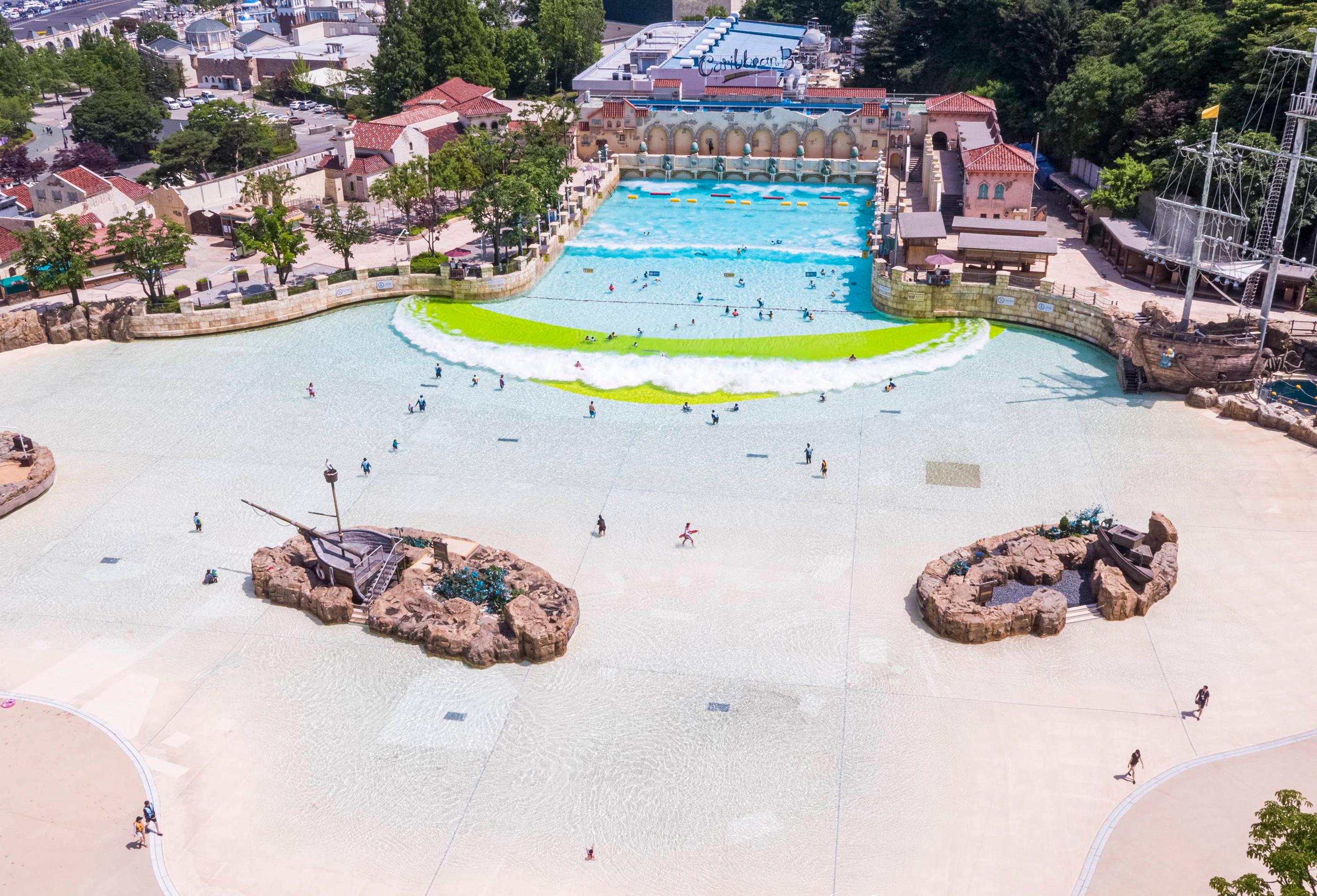 Großes Wellenbecken in Caribbean Bay, das Menschen beim Schwimmen und Surfen zeigt
