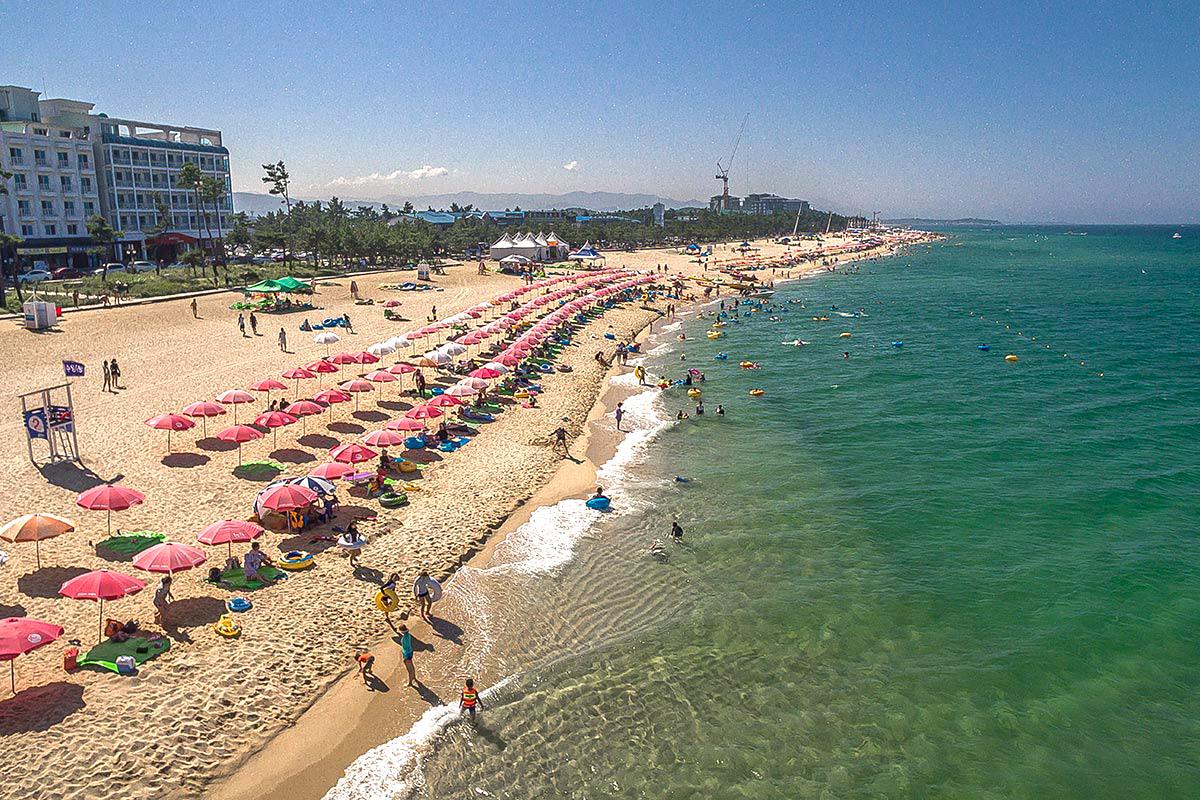 Playa Anmok en Gangneung con sombrillas rosadas y coloridas, un destino popular para los que buscan sol y mar.