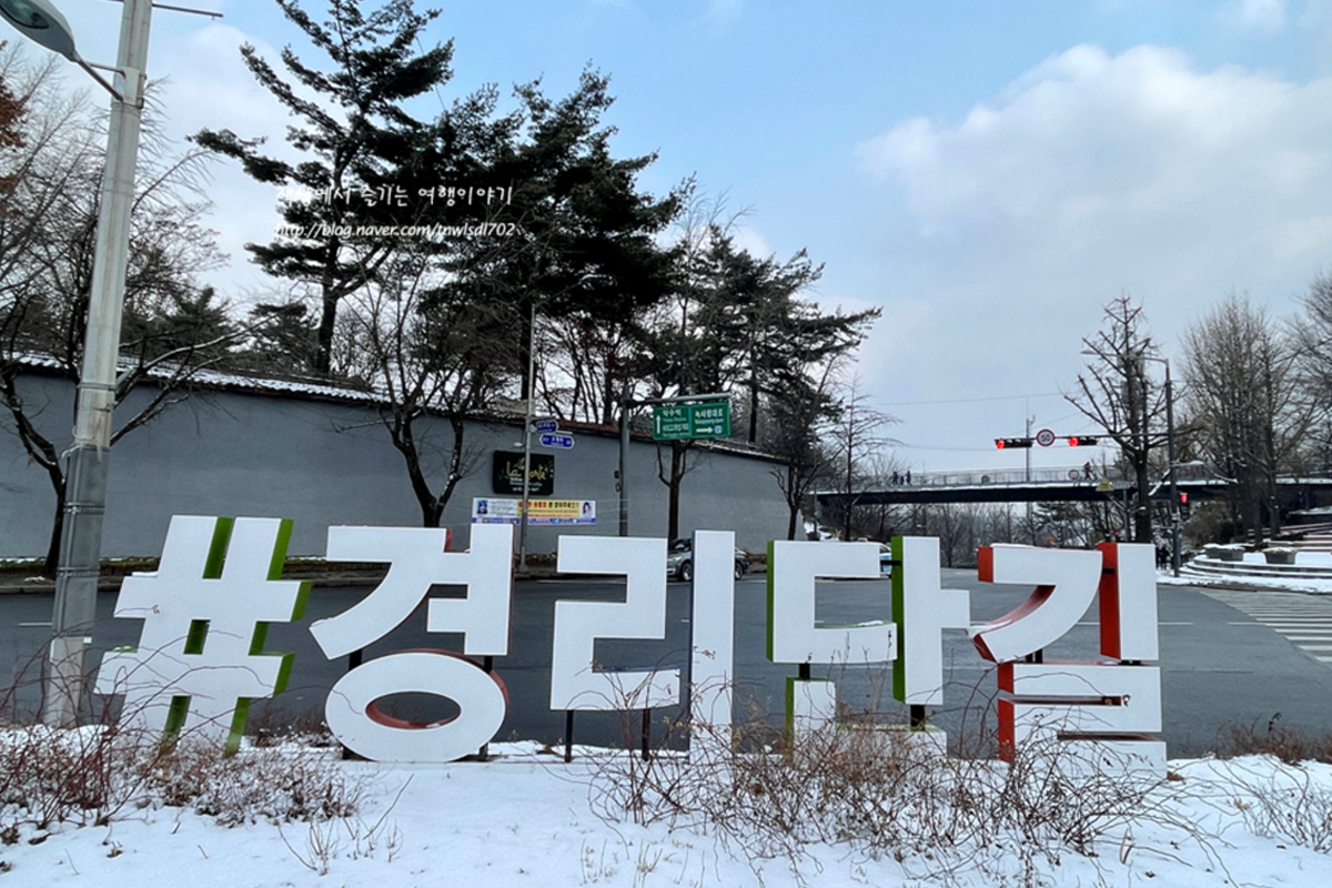 韩国首尔龙山区的经理团路标志，背景是一片雪地和冬季景色的树木。