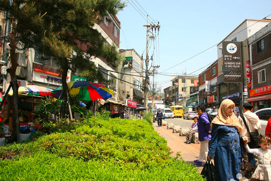 首尔经理团路的街景，这里有开着五彩缤纷太阳伞的露天商店和街头行人。