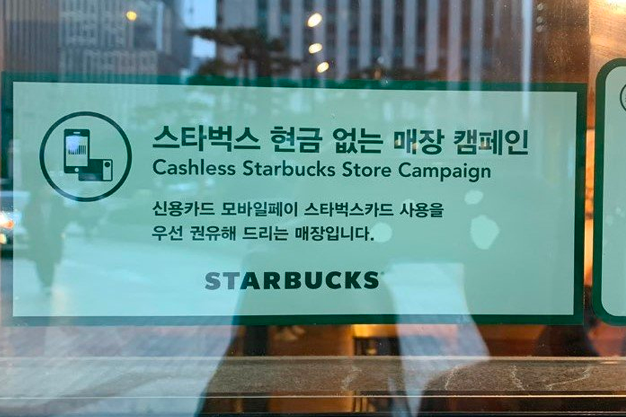 展示“无现金购物”标志的星巴克门店玻璃，体现了韩国部分商店只接受卡支付的趋势。