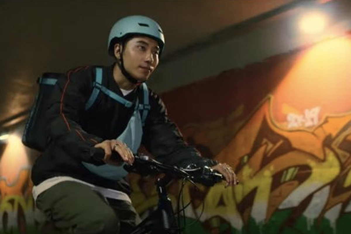 韓劇場景中角色騎自行車送貨，展示韓國斜槓族經濟活動