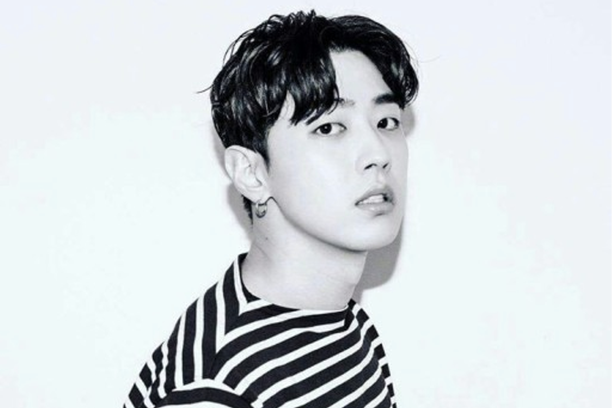 身穿条纹T恤的音乐制作人，从侧面拍摄，背景为纯白色。