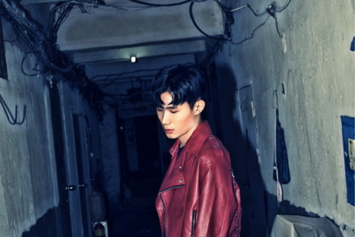 身穿红色机车夹克的男子站在昏暗的走廊里，背景是老旧建筑结构。