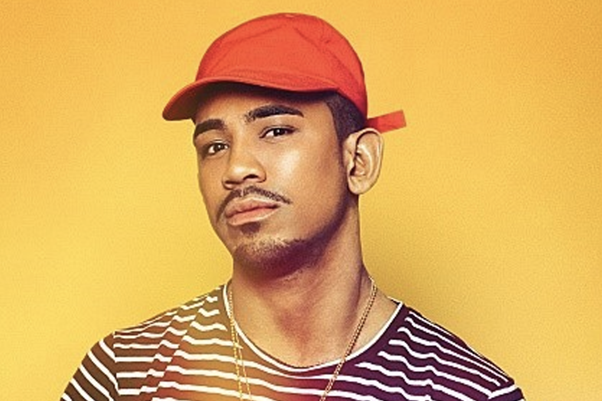 帽子上有Logo的男子，穿着条纹T恤，背景为橙黄色。