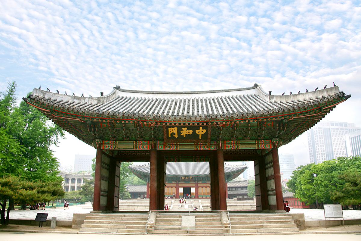 L'entrée majestueuse de Junghwamun du Palais Deoksugung, avec un ciel bleu et des détails traditionnels.