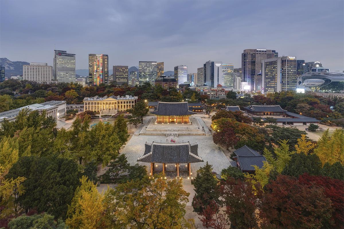 Vue aérienne du Palais Deoksugung à Séoul, entouré de la ville moderne et du parc verdoyant.