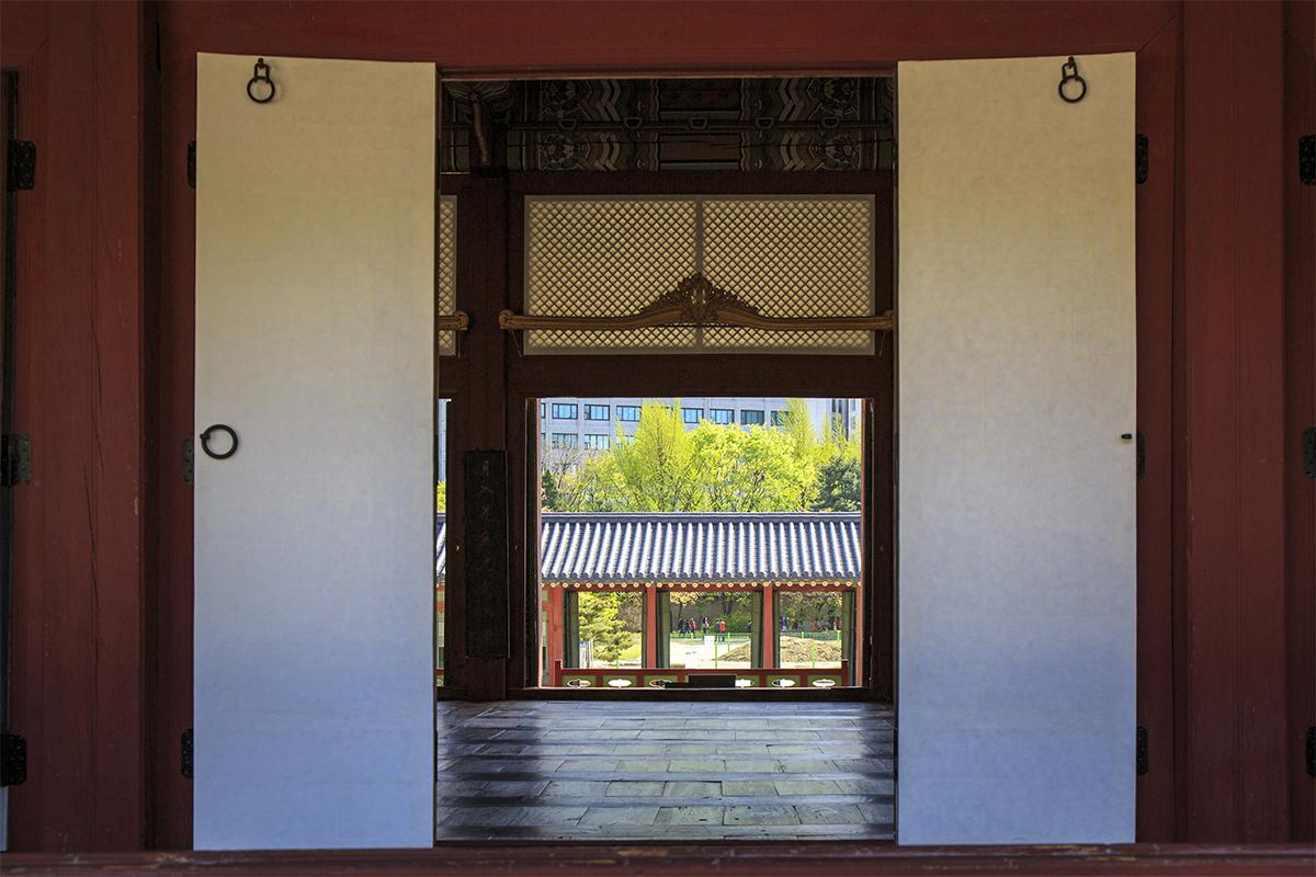 Vue intérieure d'un bâtiment traditionnel au Palais Deoksugung, avec une porte ouverte sur le jardin.