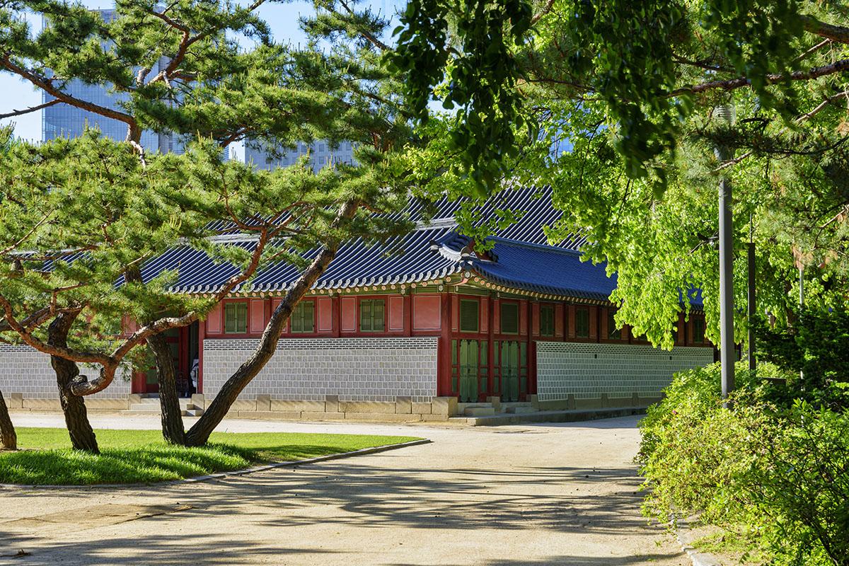 Jardin verdoyant autour du Palais Deoksugung avec arbres et pavillon traditionnel coréen.