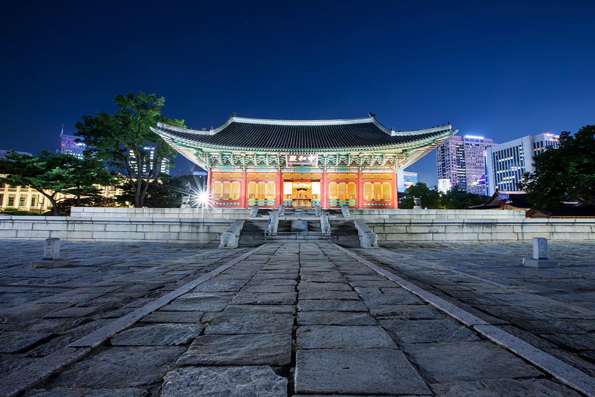 Vue nocturne du bâtiment principal Junghwajeon du Palais Deoksugung, illuminé et entouré de l'architecture coréenne.
