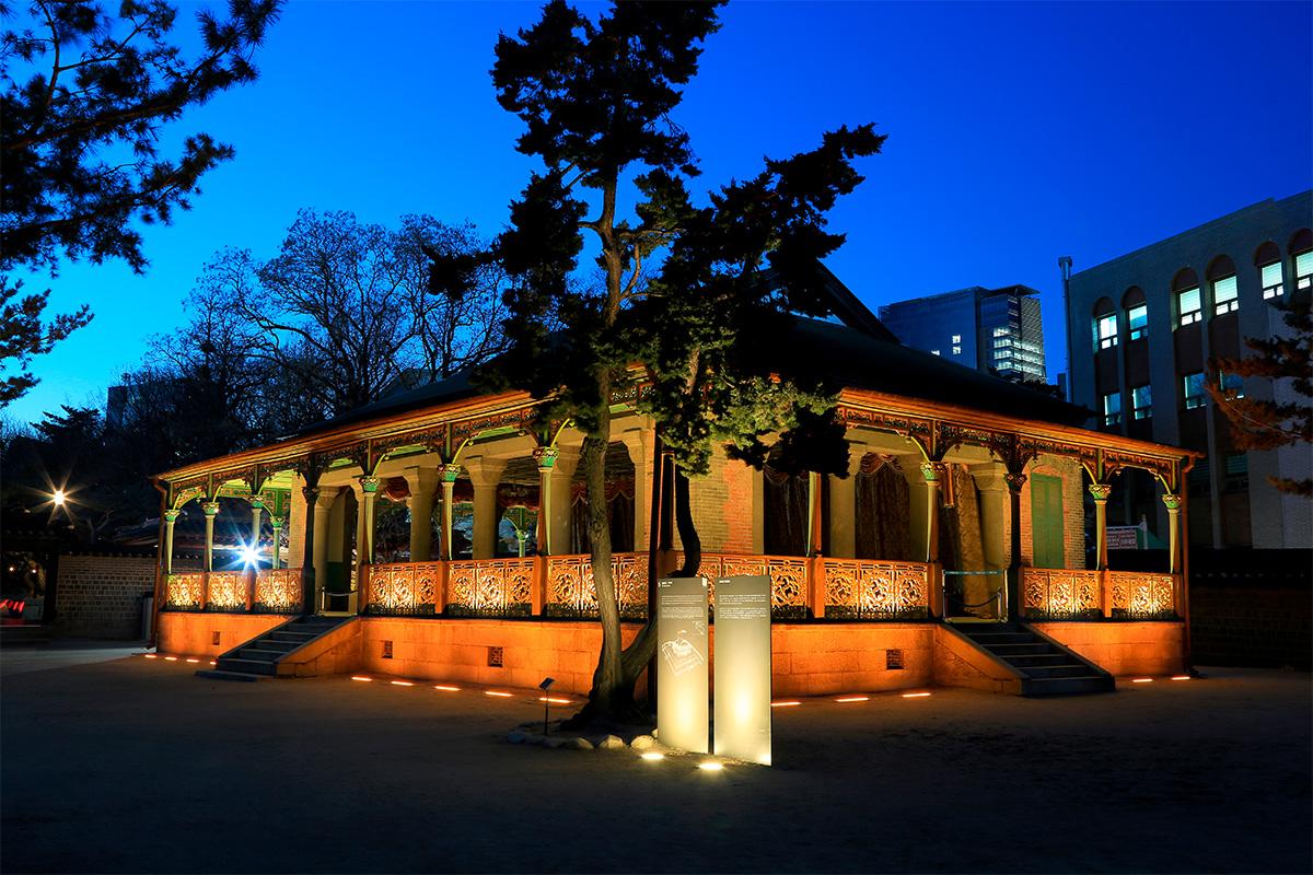 Jeonggwanheon du Palais Deoksugung, illuminé la nuit et montrant son mélange architectural unique.