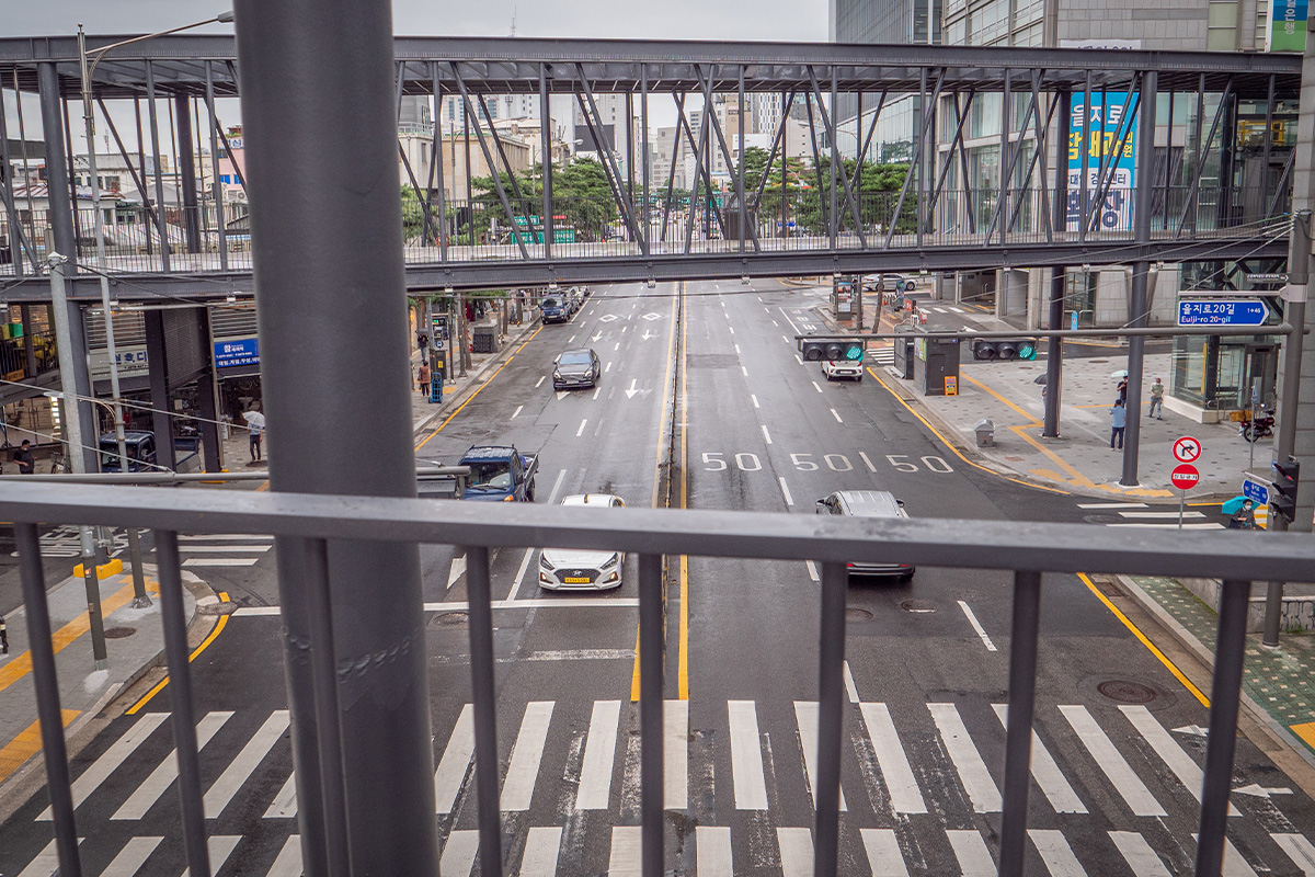 Vista de una calle transitada desde un puente peatonal en Seúl, mostrando el tráfico urbano y la infraestructura moderna.