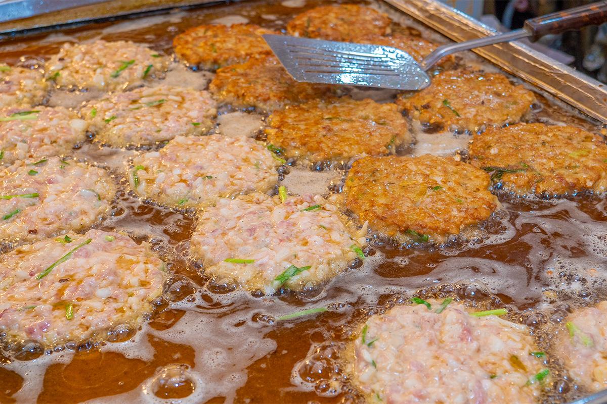 Empanadillas coreanas friéndose en un mercado de Seúl, destacando la comida callejera tradicional.