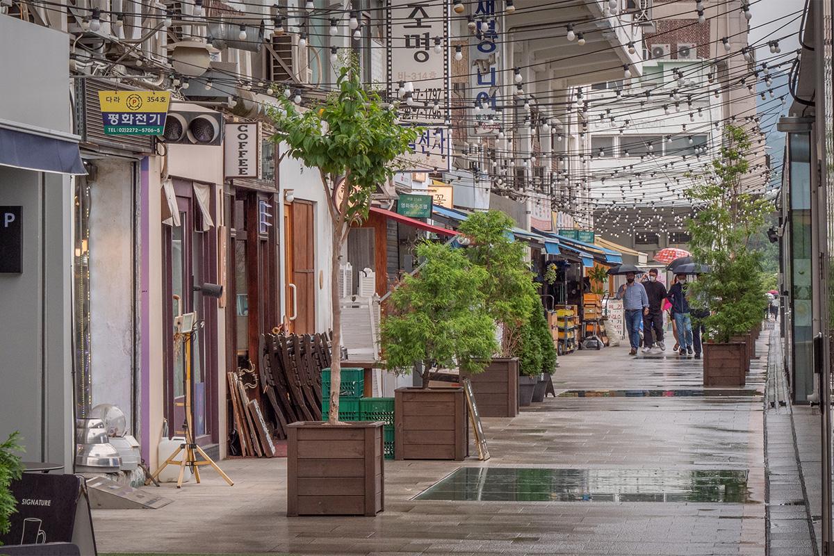 Calle de Euljiro, Seúl, bordeada de cafés y tiendas vintages con un ambiente acogedor en un día lluvioso.