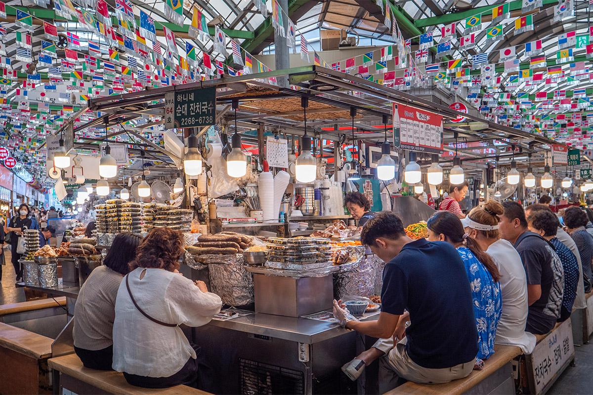 Mercado tradicional en Seúl con puestos de comida coreana típica, lleno de actividad y variedad de productos.