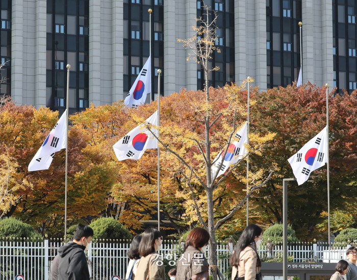 首尔市政府前降半旗追悼梨泰院踩踏事故受害者，背景是秋季的树木和建筑。