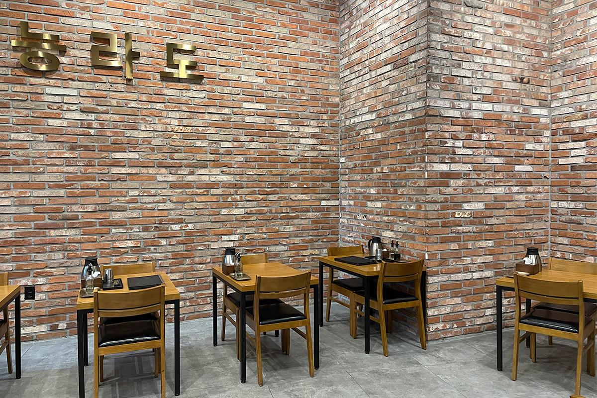 绫罗岛餐馆内独立座位区，适合少数人或者单人用餐，背景为砖纹墙壁。