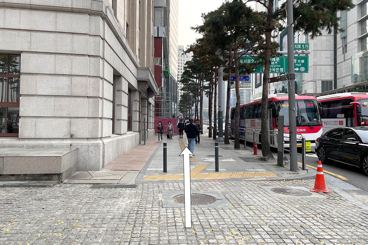 沿着首尔宽敞的街道，朝着绫罗岛餐馆的步行路径，右侧可见公交车站。