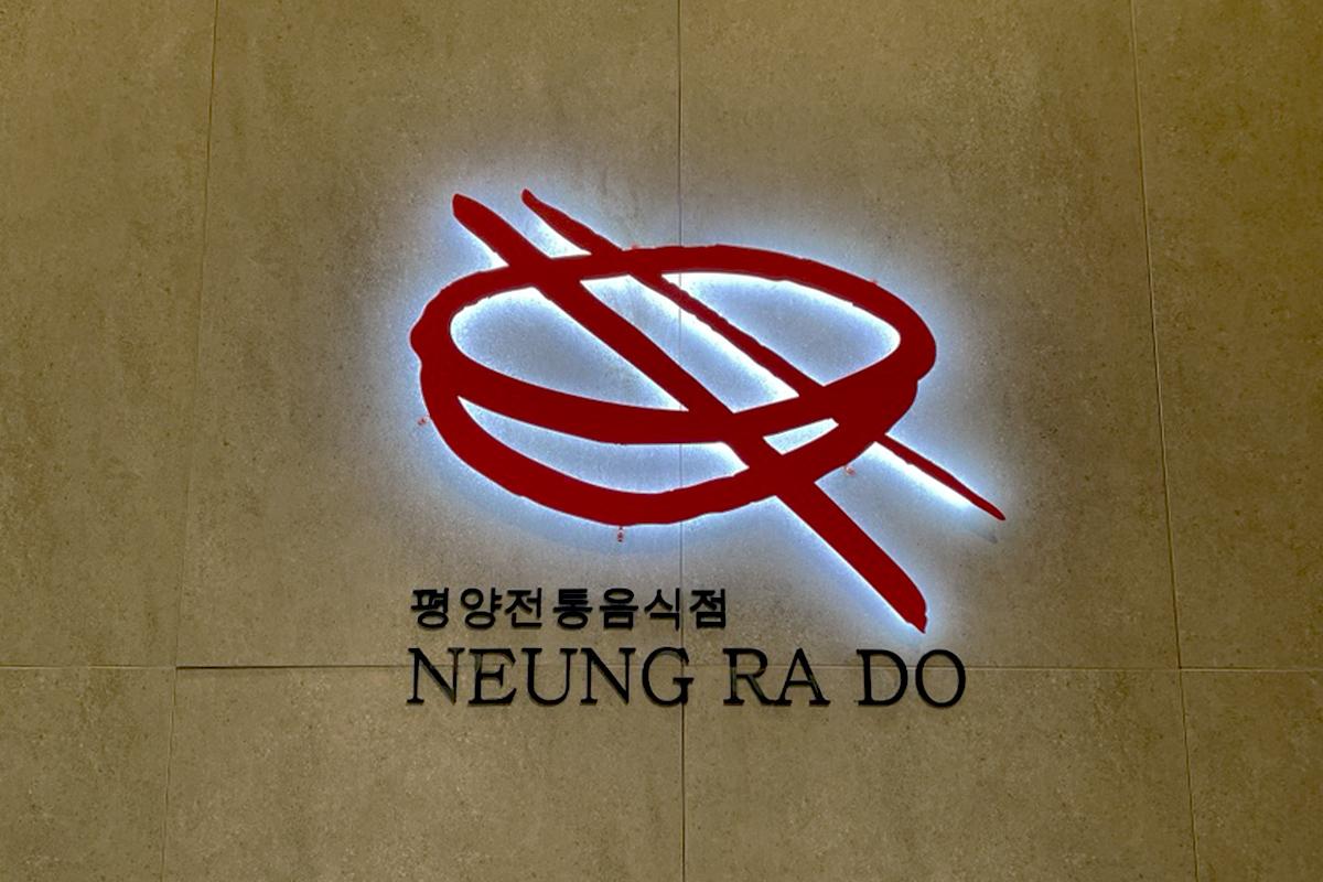 绫罗岛餐馆的标志，在墙壁上以韩国传统书法风格展示。