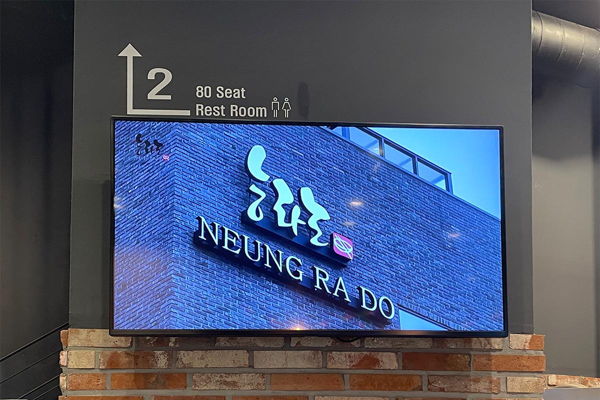 绫罗岛餐馆内显示有80个餐位的楼层指示牌，也可看到由砖墙装饰的背景。