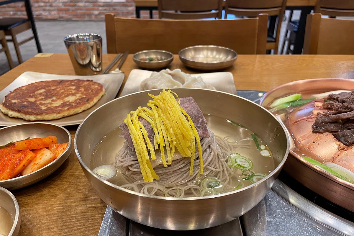 绫罗岛餐馆为顾客准备的丰盛韩味，包含平壤冷面与传统韩牛烤肉的丰盛组合。