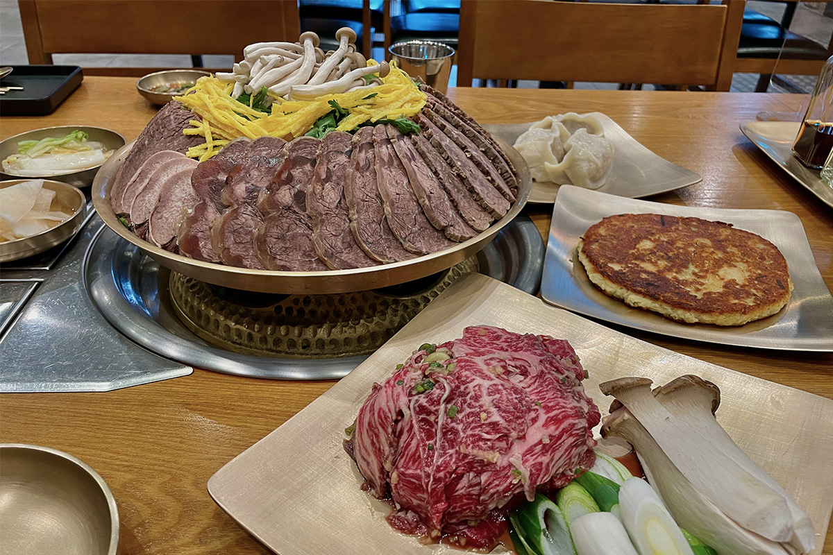 绫罗岛餐馆内的菜单展示不同韩式菜品，包括牛腹争盘和平壤冷面等特色美食。