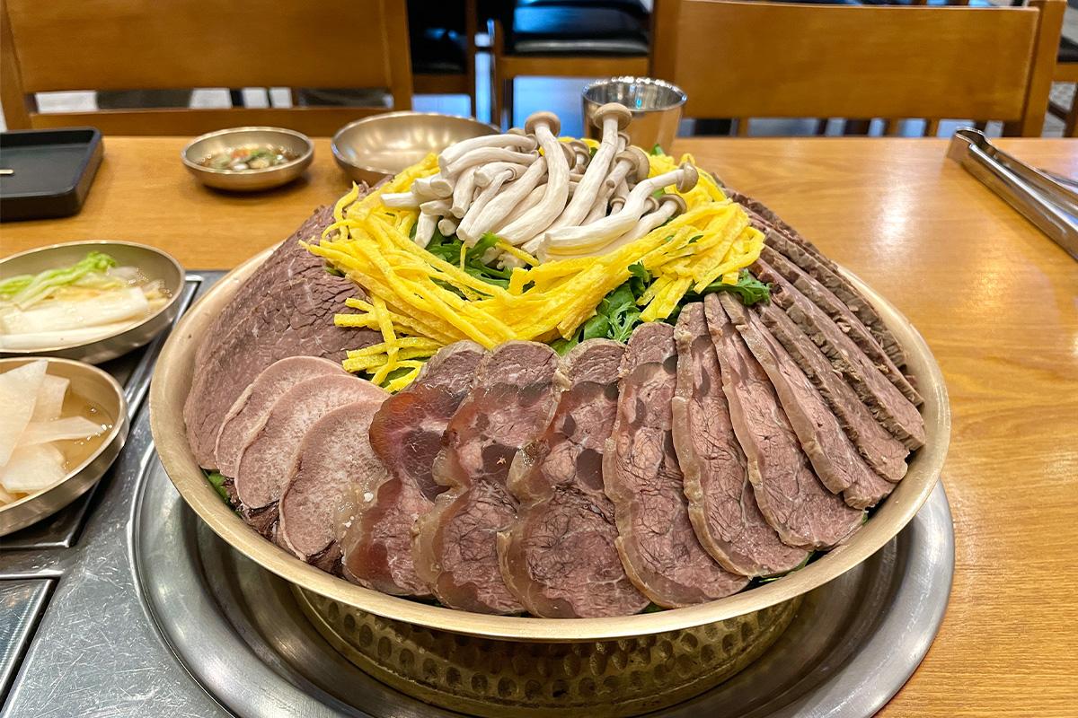 韩国传统牛腹争盘，展示了各种切片肉，与新鲜蔬菜和蘑菇搭配，奢华且让人食欲大开。