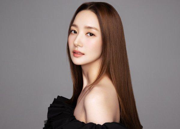 肩に掛かるストレートの長い茶色の髪を持つ女性の横顔、黒いドレスを着用