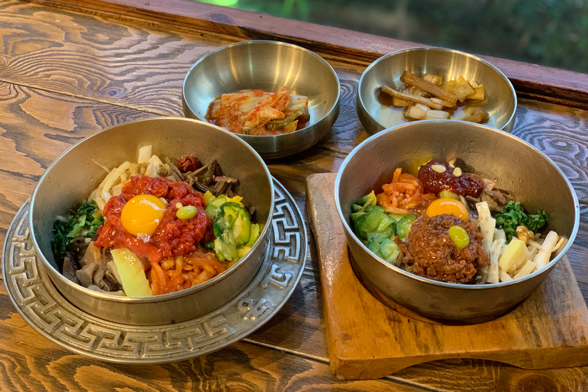 两碗色彩丰富的全州拌饭和小菜，展示出正宗美味的韩式料理。