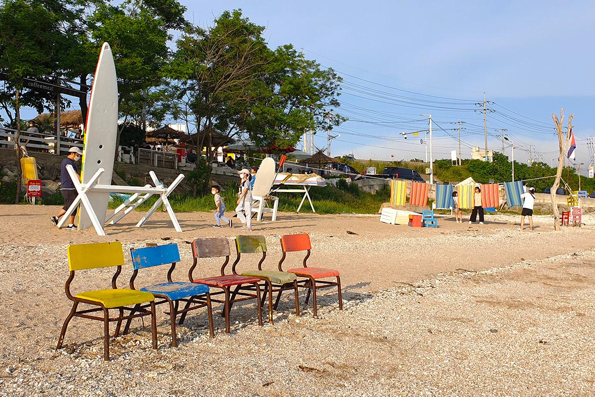 Seaside scene at Dangneomeo Beach with colorful beach chairs and surfboards set up on the sand, creating a picturesque view.