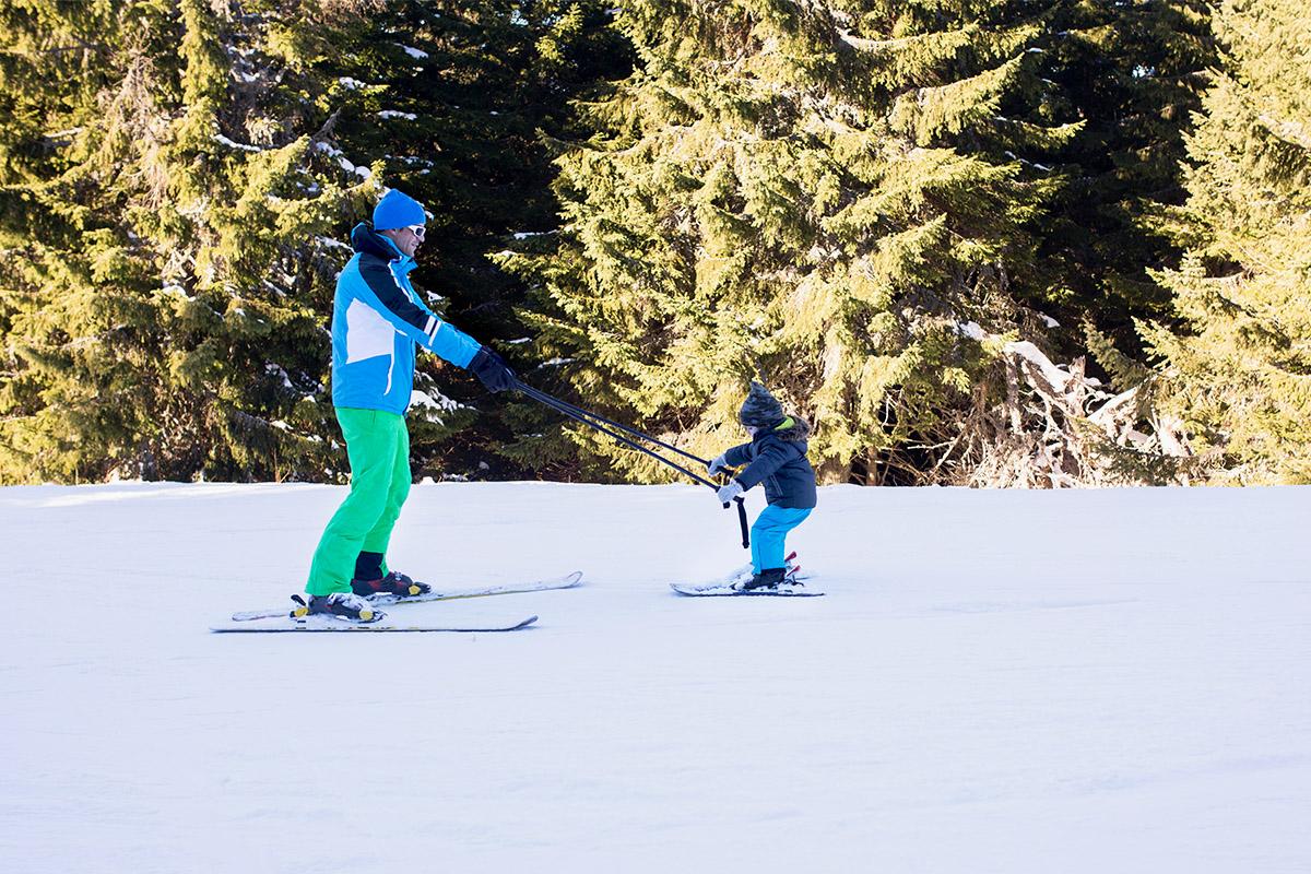 Ski instructor guiding a child on the snow, illustrating the beginner ski lessons offered at Yongpyeong Ski Resort.