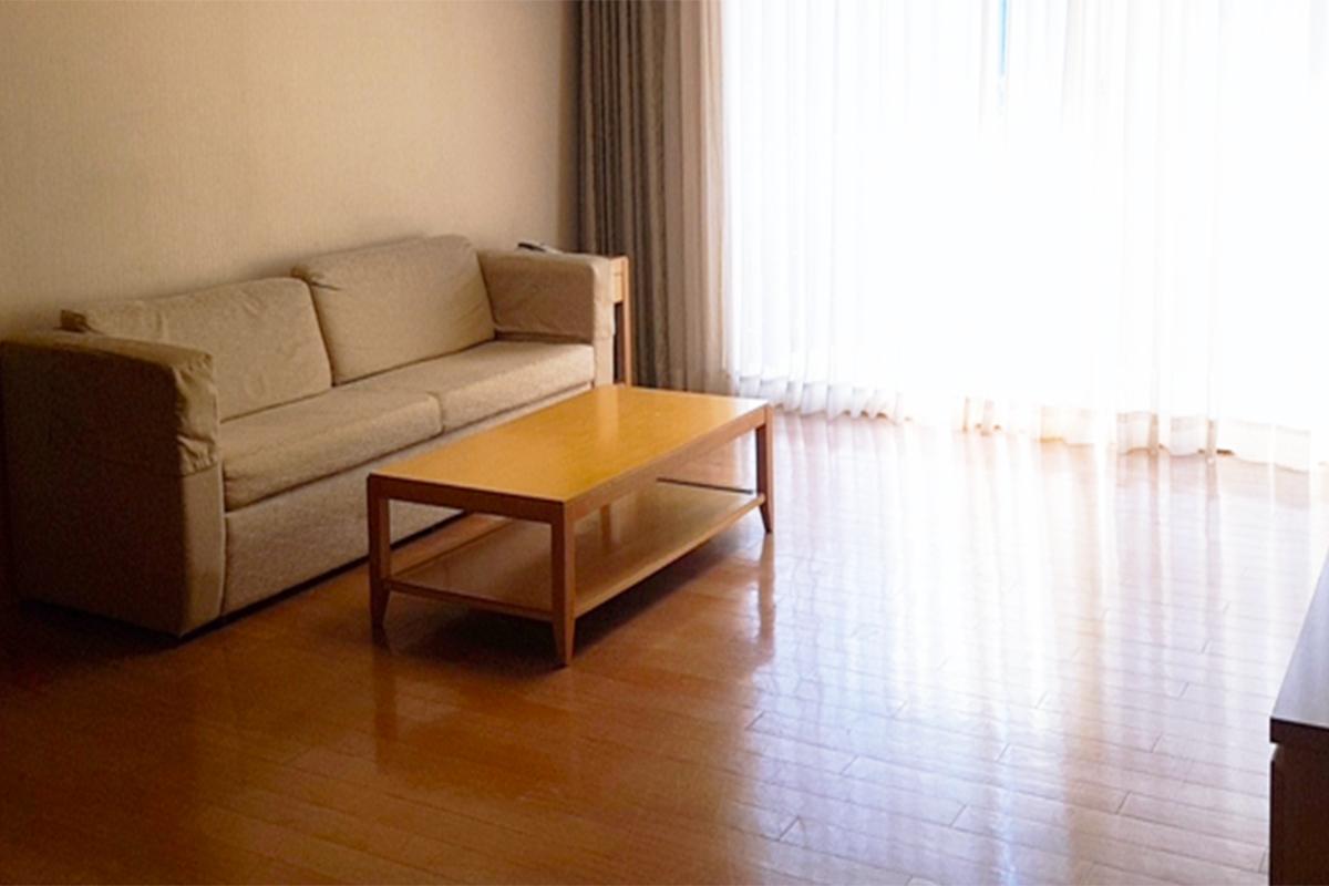 Living area with a sofa and coffee table illuminated by sunlight through a window.