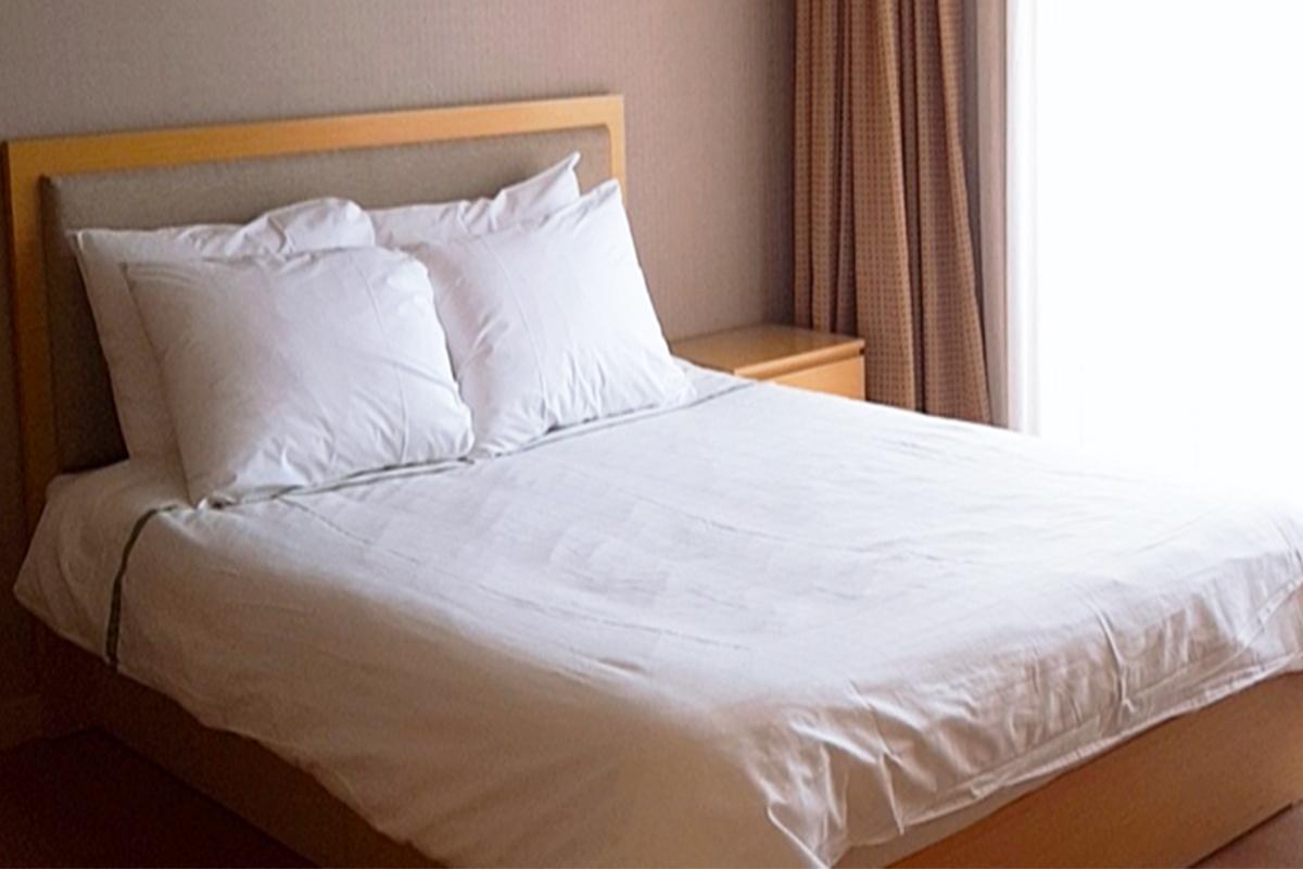 Minimalist bedroom with a double bed and crisp white linens in a hotel.