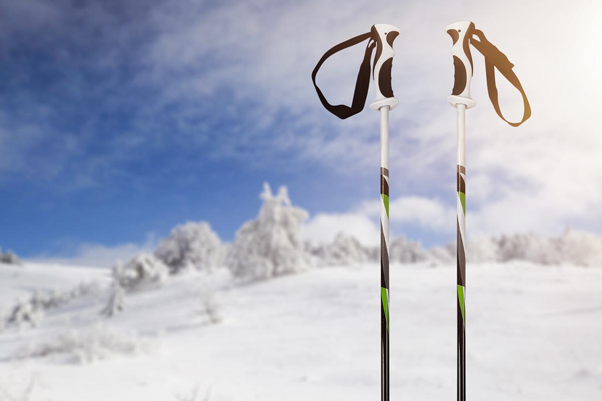 Pair of ski poles standing in the snow with a background of snowy hills, representing the ski equipment available at Yongpyeong Ski Resort.