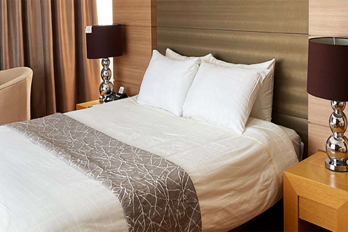 Cozy double bed hotel room with a window and two bedside lamps.