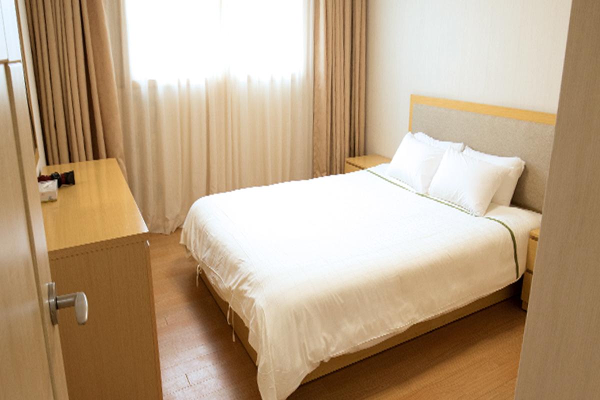 Bright hotel bedroom featuring a double bed and curtains drawn open to let in natural light.