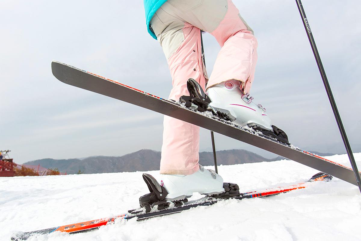 Close-up of person in skiing gear including pink and white boots on skis, ready to ski at Yongpyeong Ski Resort.