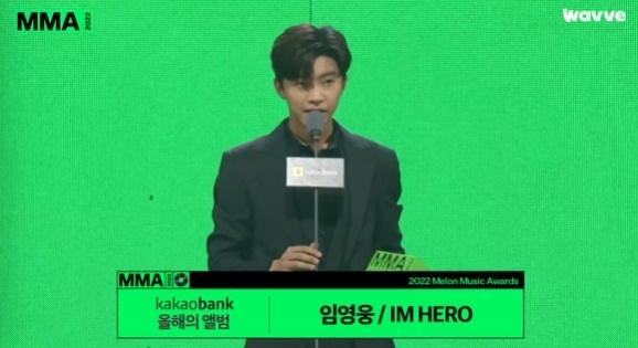 2022年のMelOn MUSIC AWARDSでイム・ヨンウンが授賞した瞬間。彼は今年のアルバム賞を受賞した。「IM HERO」での感動的な瞬間を切り取った写真。鮮やかな背景が彼の気持ちをより一層引き立てている。