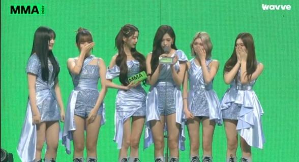 IVEのメンバーがMMA2022で「LOVE DIVE」で今年のベストソングを受賞した際のスピーチシーン。メンバーたちの表情は喜びに溢れており、その瞬間を記録した写真。