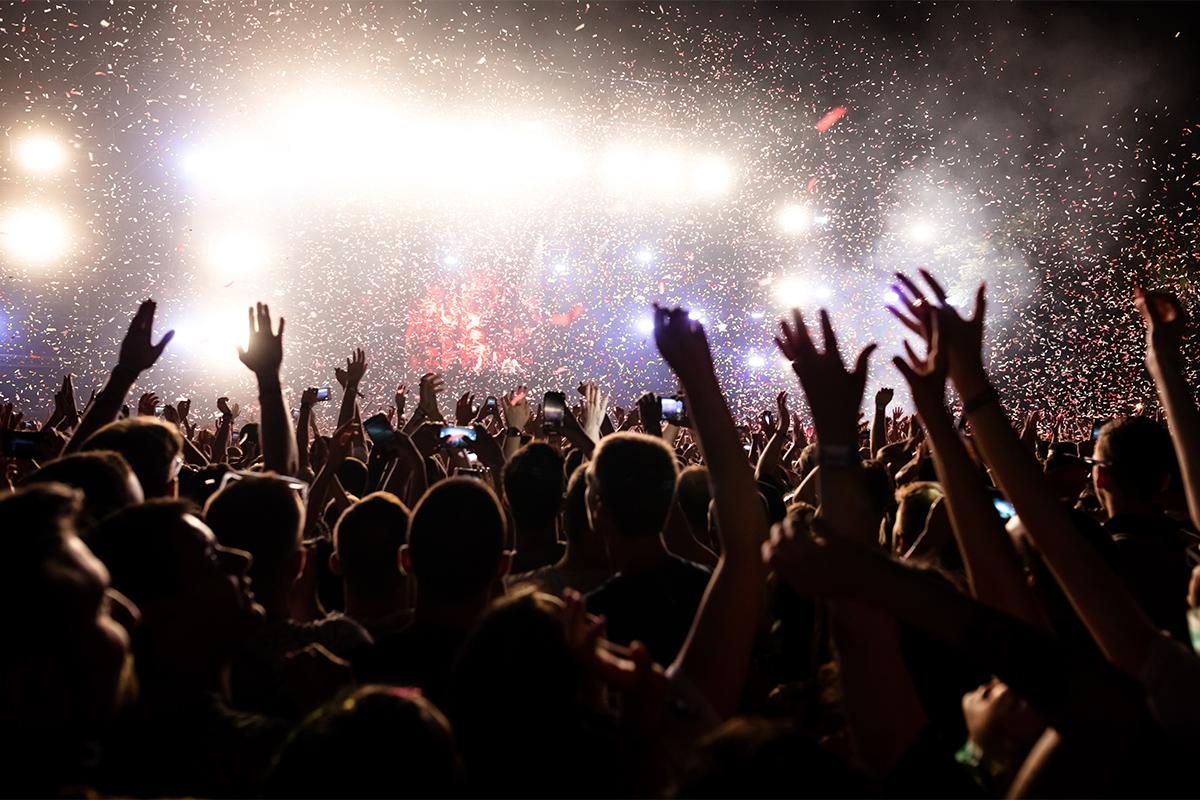 Толпа людей на большом концерте с поднятыми руками и конфетти