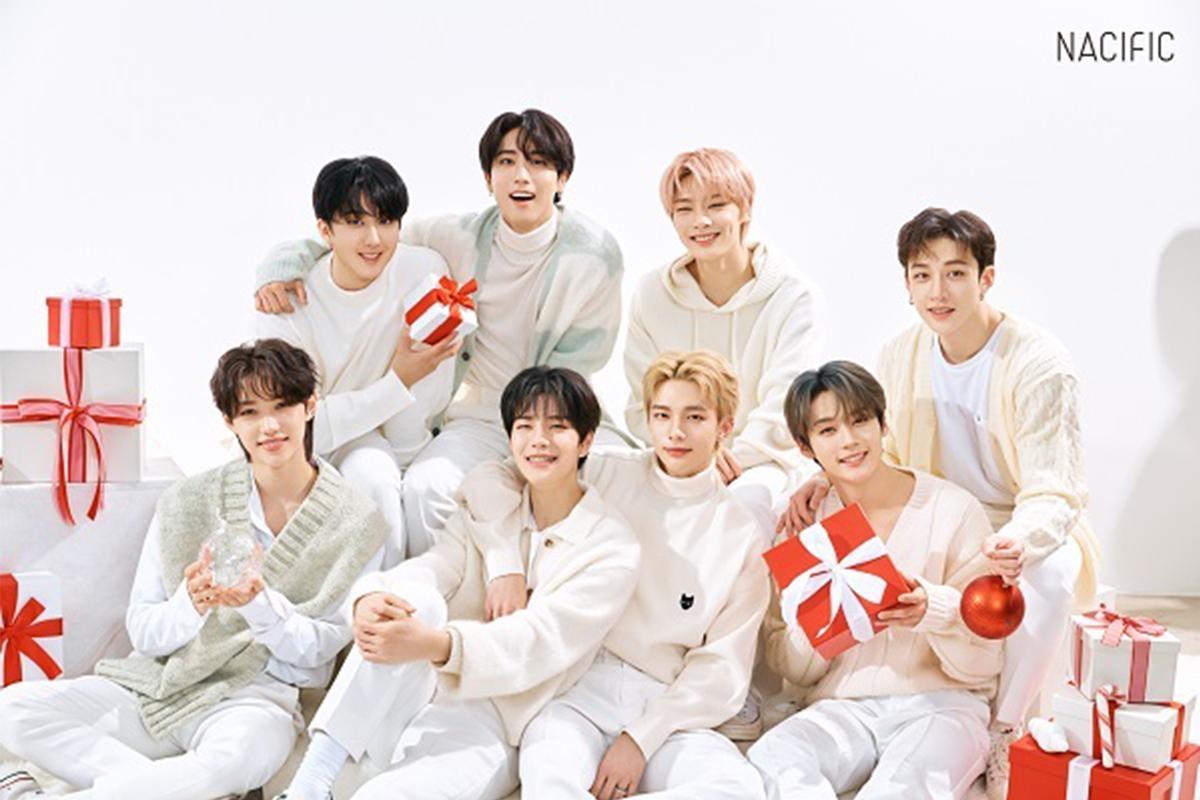 Промо-фото группы Stray Kids в белом, с подарками на фоне рождественских декораций