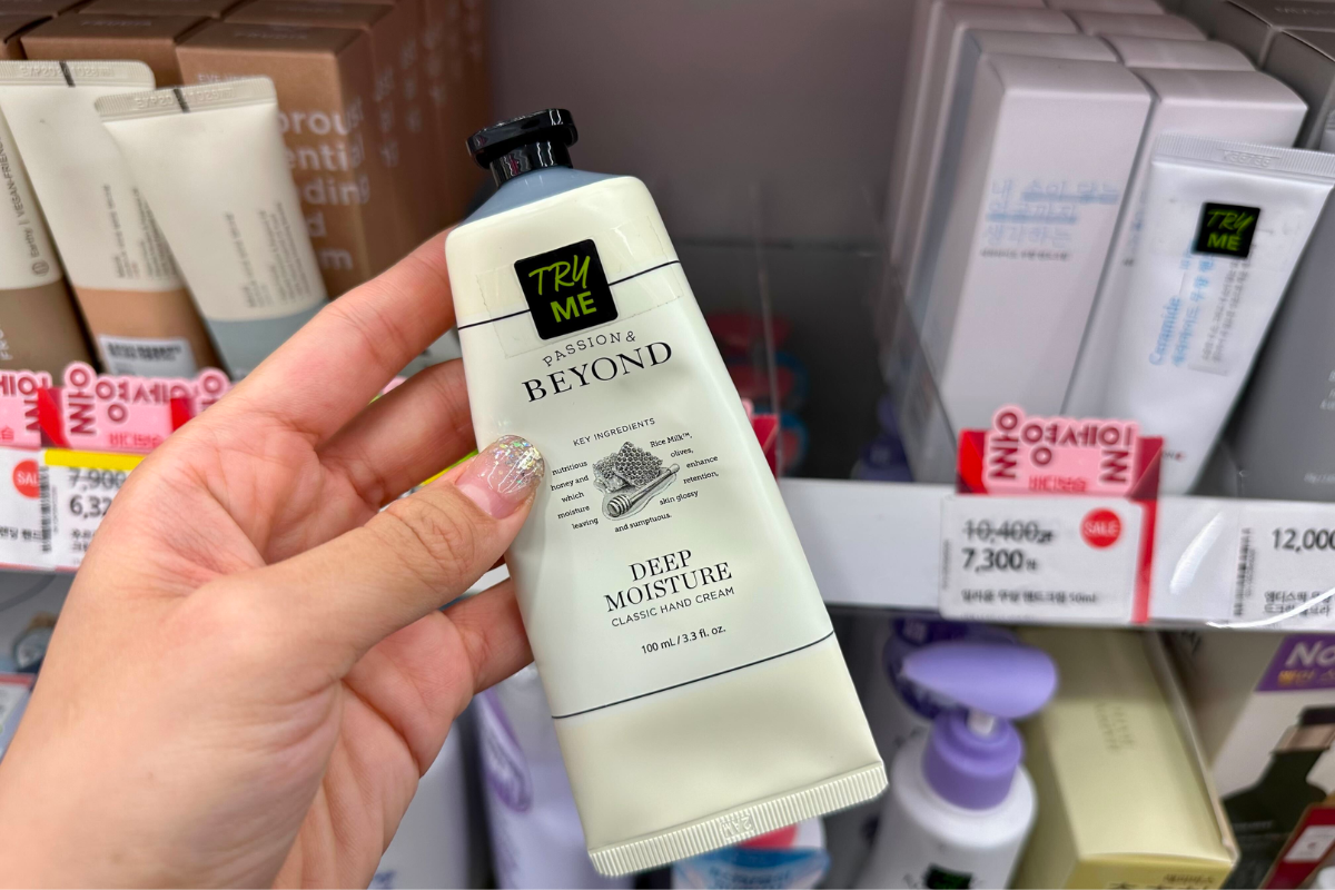 Kem dưỡng tay BEYOND Classic Deep Moisture cầm trên tay, trưng bày tại cửa hàng Olive Young, có thành phần dưỡng chất từ sữa gạo và mật ong, giá cả phải chăng.