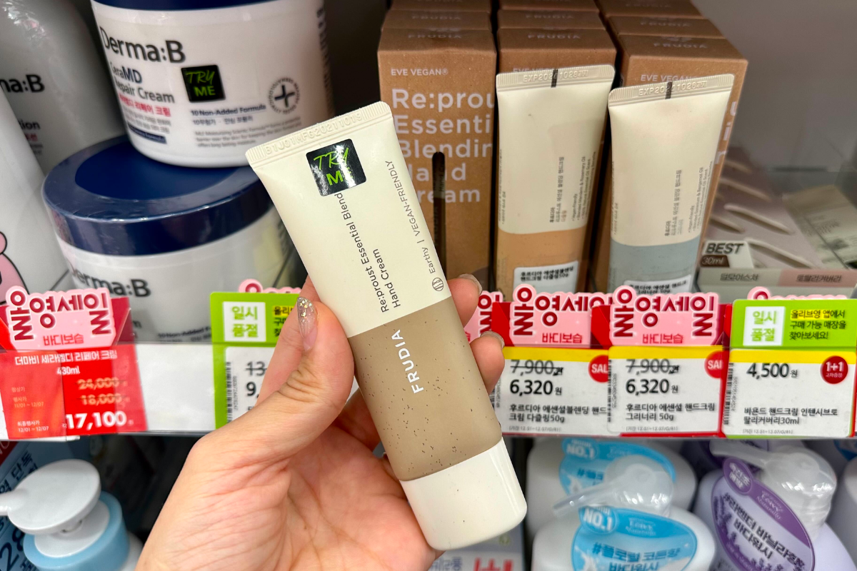 Kem dưỡng tay FRUDIA My Orchard Hand Cream Rich Nourishment cầm trên tay, bày bán tại Olive Young, nổi bật với thành phần tự nhiên từ trái cây và chất kem mềm mịn.