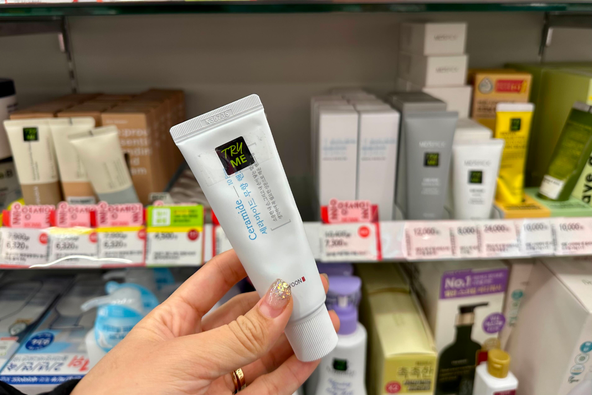 Kem dưỡng tay Illiyoon Ceramide 10 Free cầm trên tay, trưng bày tại cửa hàng Olive Young với bảng giá và chương trình khuyến mãi, sản phẩm an toàn và không có mùi phù hợp cho da nhạy cảm.