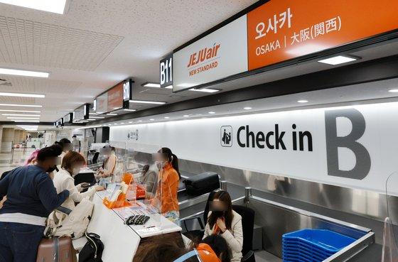 韓国の金浦空港での大阪行き航空便のチェックインカウンター、旅行者が手続き中。日韓航空便の回復を示すイメージ。