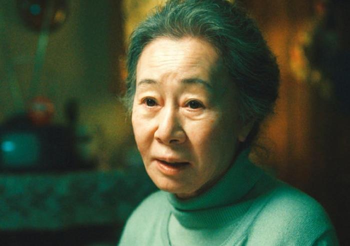 ドラマ『パチンコ』でのシーンを撮影する映画セットの背景。ブラーされた人物の背後には、年代物のテレビと装飾が見える。